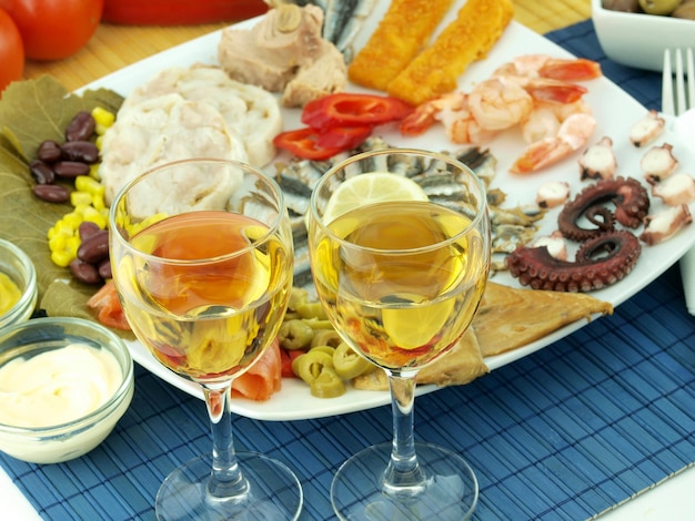 Two glasses of wine are on a table with a plate of food.