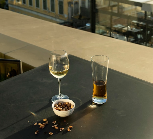 Two glasses of wine and a bowl of peanuts are on a table.