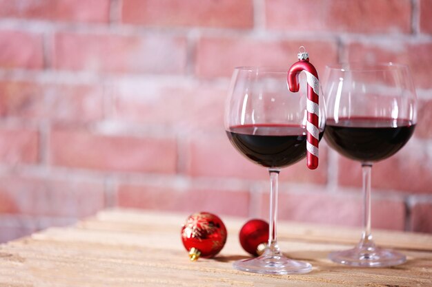 Two glasses of wine with christmas toys on wall surface