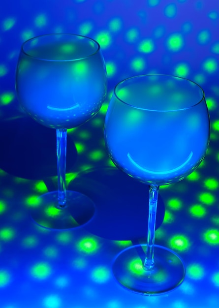 Two glasses with an alcohol vapors of vodka in a blue light on a blue background