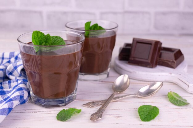Two glasses with chocolate pudding on a white wooden background