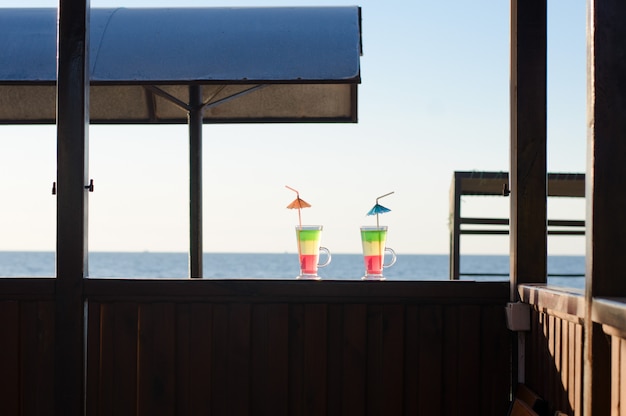 Due bicchieri con cocktail su una scrivania in legno contro il mare