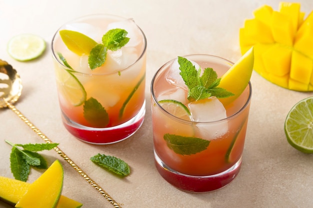 Два стакана прохладительных напитков из свежего сока манго, кубиков льда и листьев мяты. Коктейли из манго