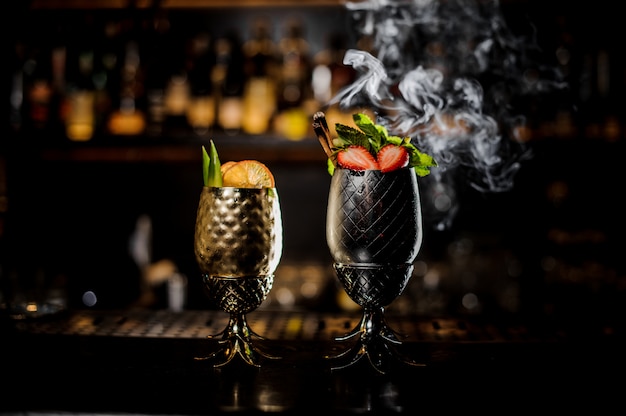 Due bicchieri con freschi cocktail estivi decorati con frutta sul bancone del bar