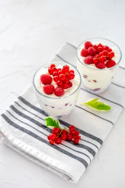 Two glasses with greek yogurt, raspberry and red currant 