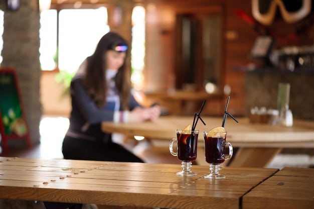 Two glasses with hot tasty mulled wine on a wooden table in the cafe