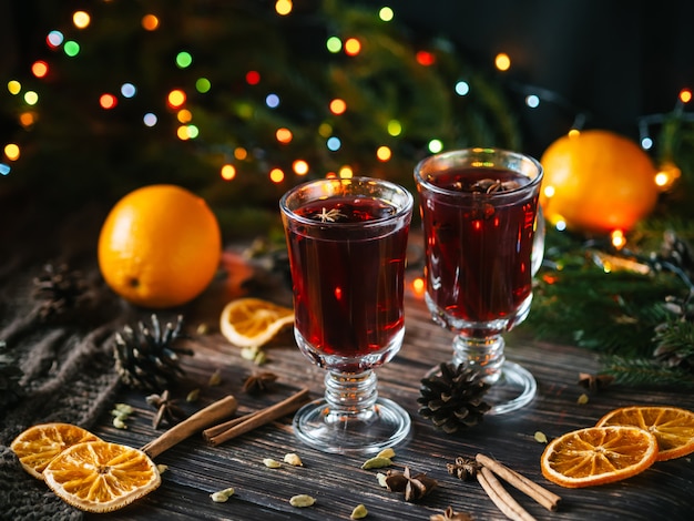 Two glasses with mulled wine on the table with orange slices and spices