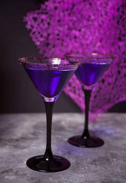 Photo two glasses with purple cocktail for halloween party on the dark