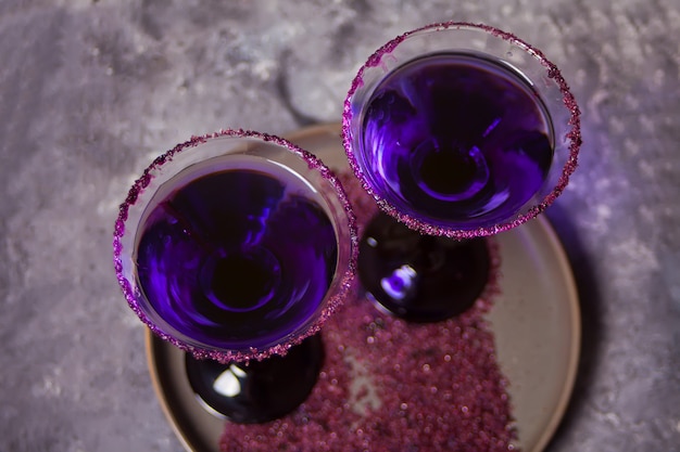 暗闇の中でハロウィーンパーティーのための紫色のカクテルと2つのメガネ