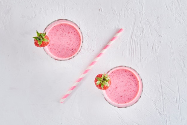 Two glasses with strawberry smoothie separated by drinking straw as percent sign. Healthy food concept