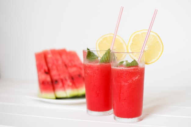 Two glasses with watermelon smoothies with lemon and mint