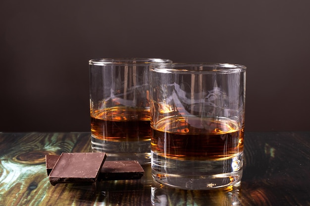 Two glasses with whiskey and pieces of dark chocolate.