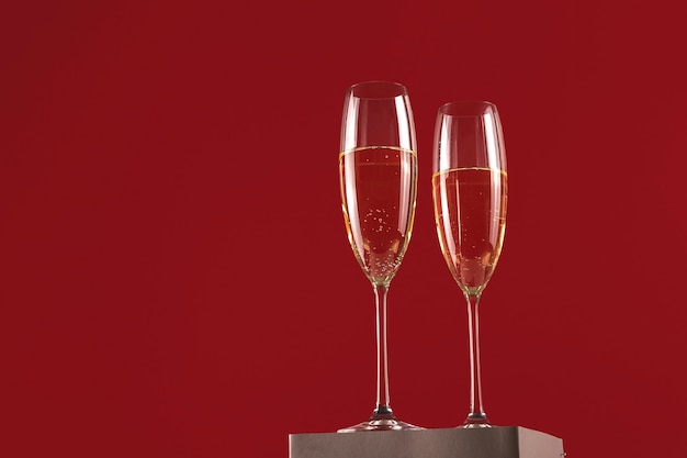 Two glassess of champagne on a stand on a red