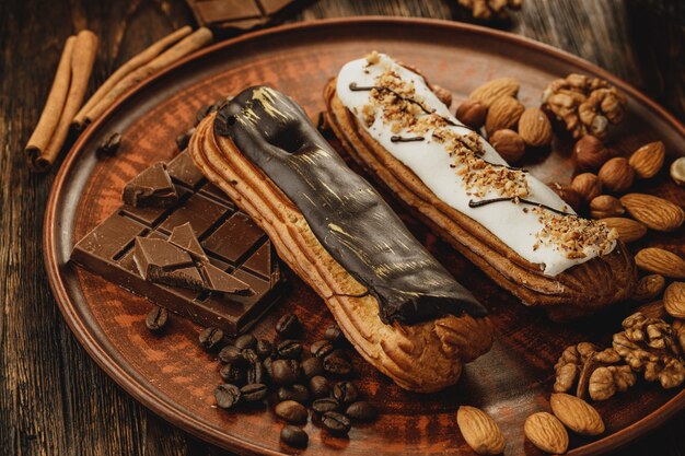 Two glazed eclairs decorated with nuts and coffee