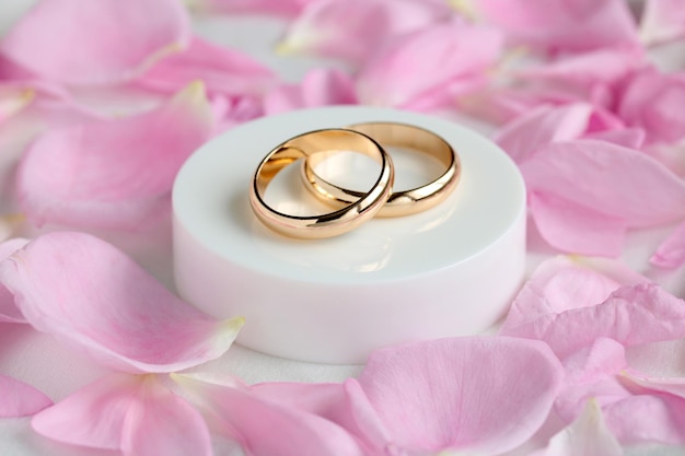 2つの金の指輪とピンクのバラの花びら