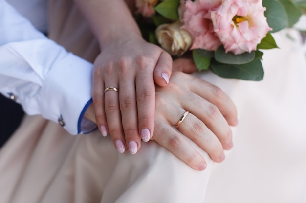 Two gold wedding rings on the hands close up . newlyweds with wedding rings on  fingers close up.