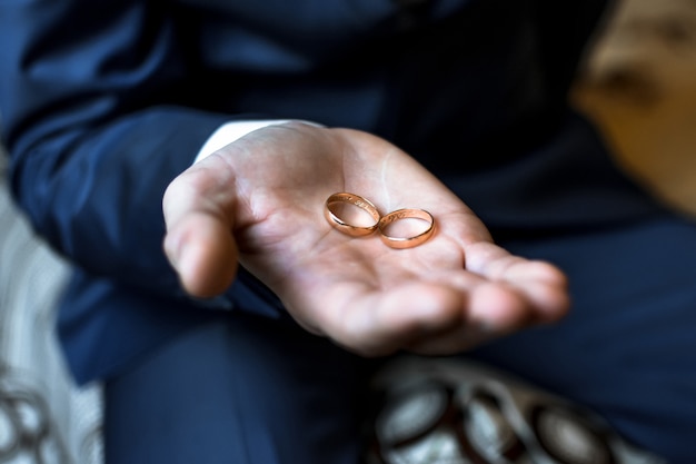 Photo two gold wedding rings in the hands of the man