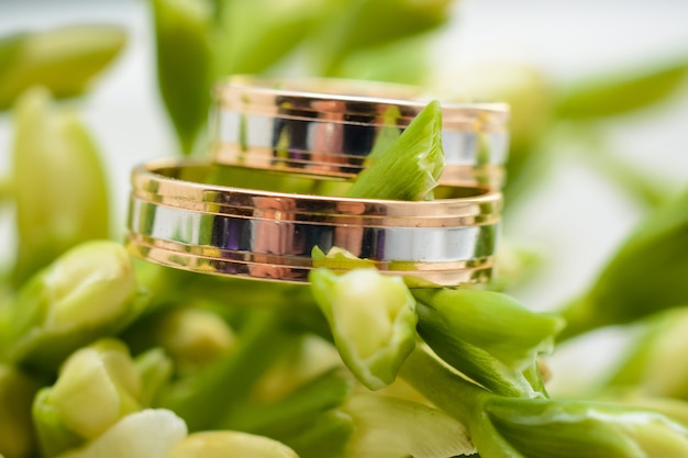 Two gold wedding rings lie on the flowers of a bouquet