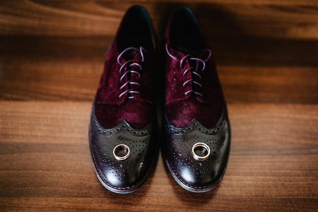 Two gold wedding rings on men's shoes on a wooden brown background Wedding rings of the bride and groom Engagement