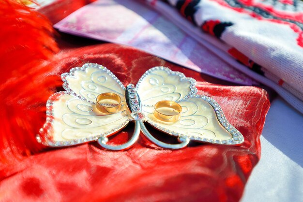 Two gold wedding rings on red pillow