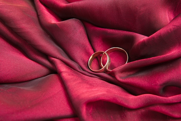 Two gold wedding rings on the red textile