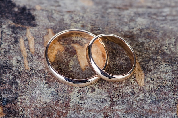 Two gold wedding rings on wooden background