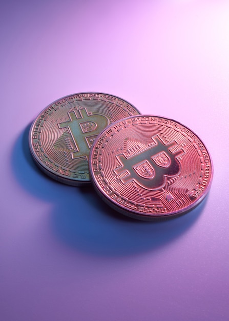 Two golden bitcoins isolated on pink purple background close-up with copy space