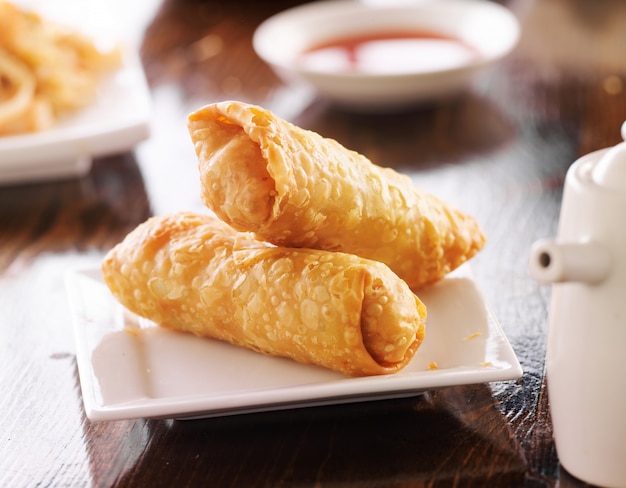 Two golden egg rolls stacked on plate