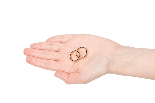 Два золотых кольца в женской руке на белом фоне