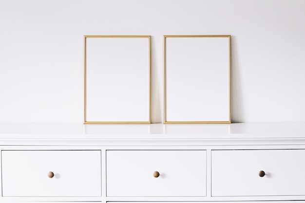 Two golden vertical frames on white furniture