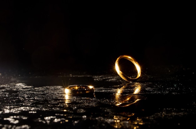 Two golden wedding rings on black background.