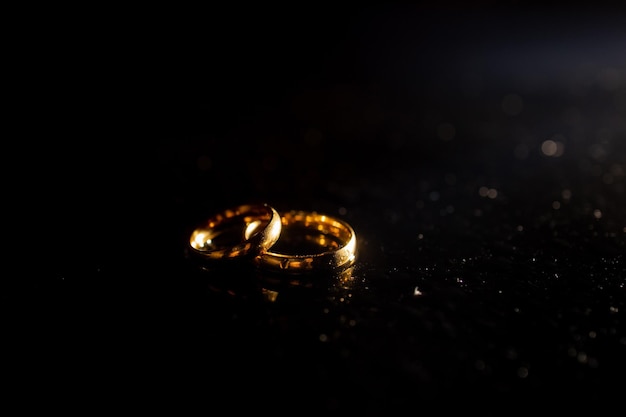 Two golden wedding rings on black background