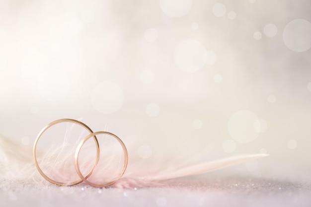 Photo two golden wedding rings and feather light soft background