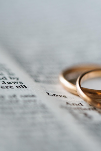 Two golden wedding rings and opened pages of holy bible represents the concept of marriage and the love between two Christians