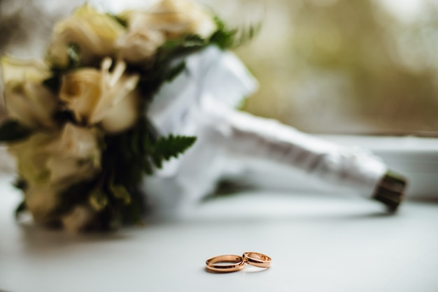 Two golden wedding rings with a bouquet