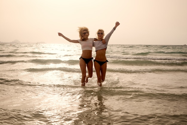 Due bellissime ragazze si stanno godendo il tramonto nel mare esotico.