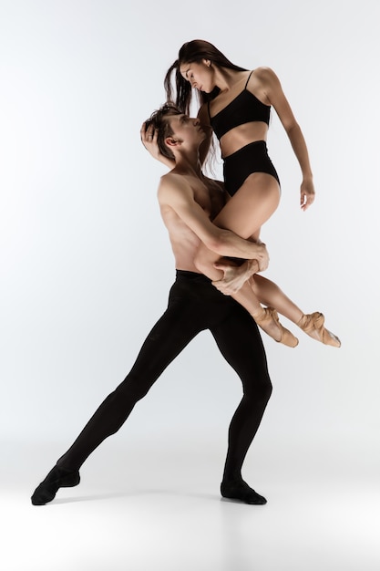 Two graceful ballet dancers man and woman in minimal black\
style dancing isolated on white background