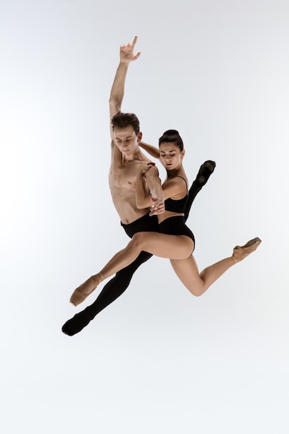 Two graceful ballet dancers man and woman in minimal black style dancing isolated on white