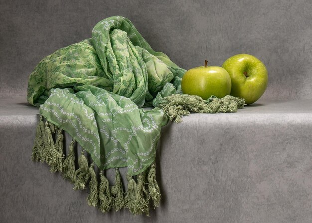 Two green apples on a gray background Next to a green scarf