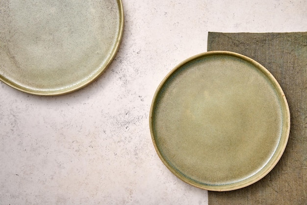 Two green plates with napkin on white textured background design concept copy space