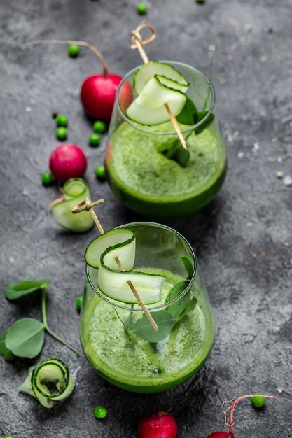 Photo two green smoothie with green fresh peas, cucumber, radish, spinach and lime. vertical image. top view.
