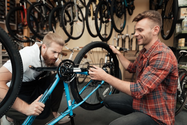 Photo two guys examine bicycle in sport workshop