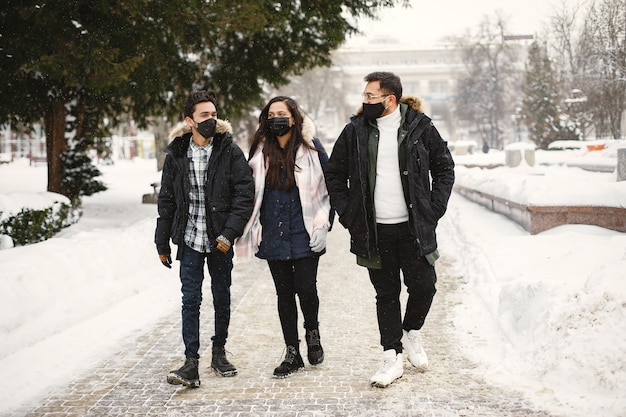 Two guys and a girl in masks. Indian friends on street. Young people in warm clothes.