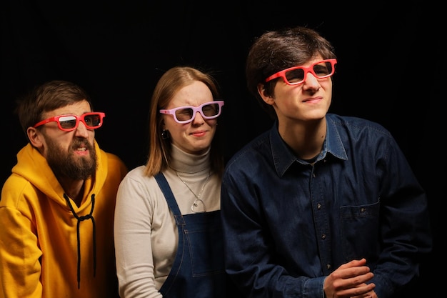 Two guys and a girl in a movie theater emotionally watch a movie Cinema Young guys in 3D glasses