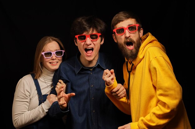 Two guys and a girl in a movie theater emotionally watch a movie Cinema Young guys in 3D glasses
