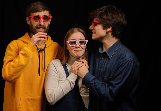 Two guys and a girl in a movie theater emotionally watch a movie Cinema Young guys in 3D glasses