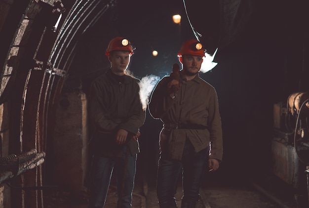 Photo two guys in special clothes and helmets standing in the mine. miners