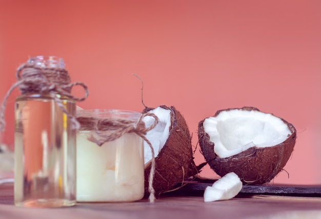 Two half of coconut and coconut oil in a bottles