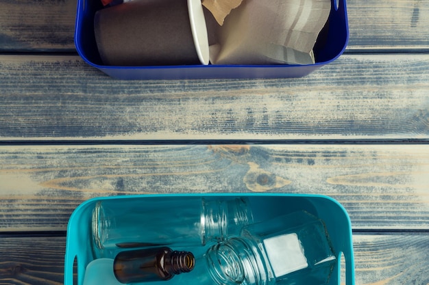 Two halves containers with waste trash on wooden table\
background recycling sort of garbage eco friendly technology