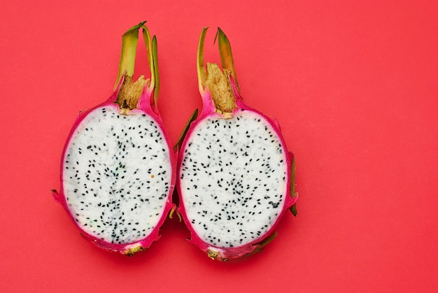 Two halves of dragon fruit on red surface